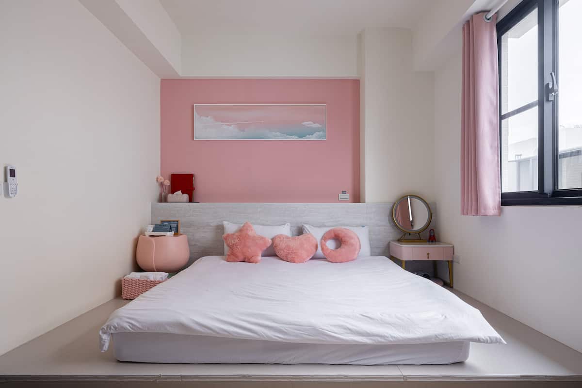 Un dormitorio moderno con cama, mesita de noche, espejo y ventana con cortinas.