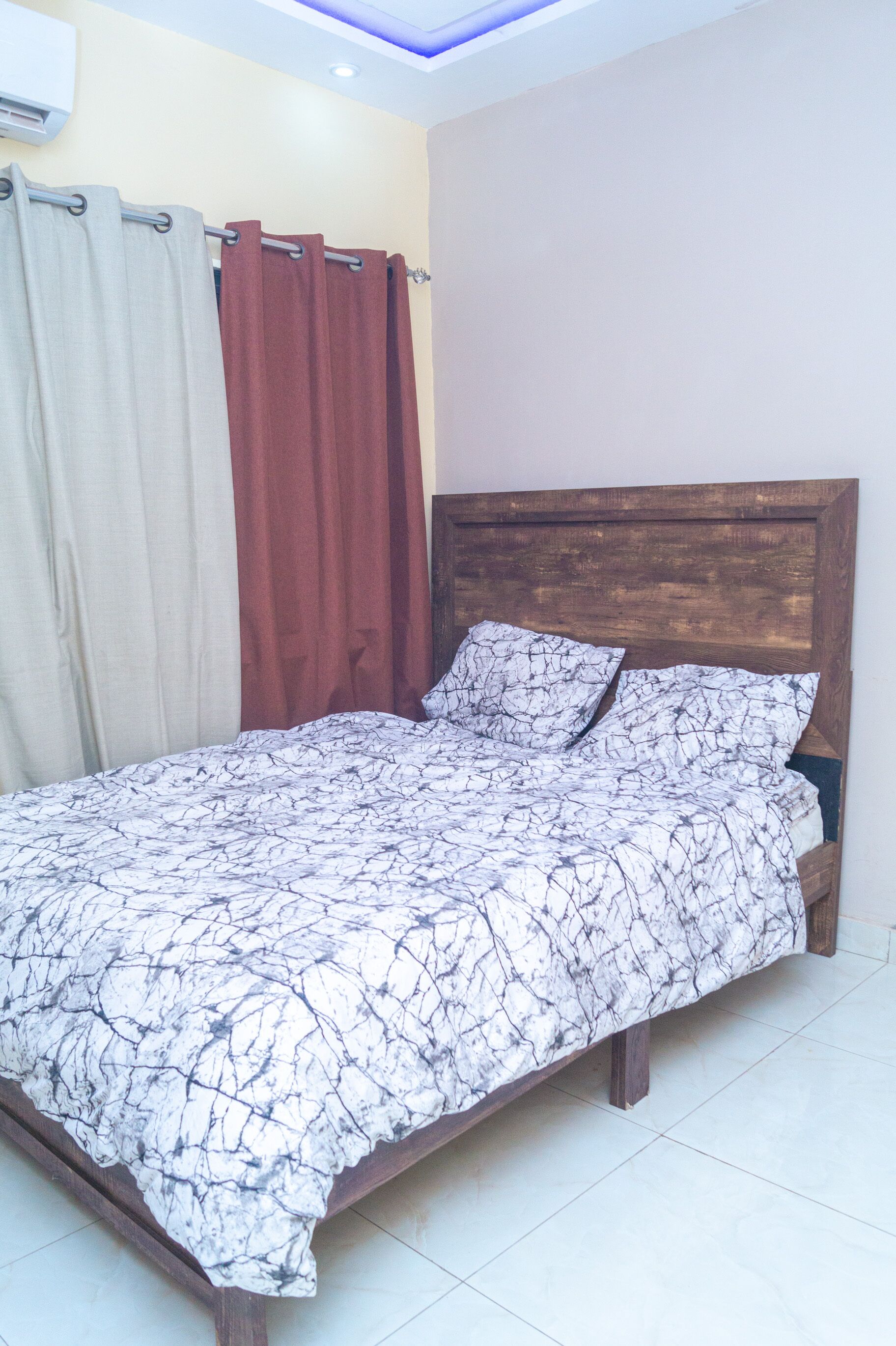 Una cama con cabecera de madera, una colcha estampada y dos almohadas.