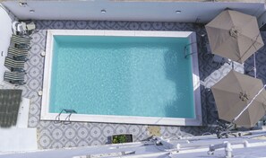 A rectangular pool with clear water, surrounded by patterned tiles. - Legacy Apartments (Brufut)