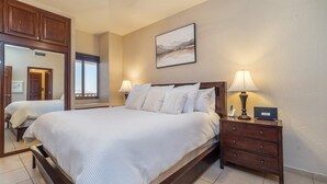 Hotellihuone, jossa on suuri sänky, kaksi yöpöytää valaisimineen, peili ja taulu seinällä.