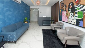 A modern living room with a blue sofa, a grey sofa, a beige sofa, a black rug, and a painting on the wall. - Casse Di Lusso  (Accra)