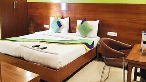 A hotel room with a bed, wooden headboard, green walls, a desk, and a chair. - The Aroma Residency near The Medanta, The Medicity, Gurgaon (Gurugram)