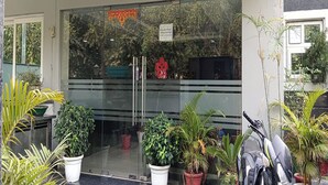 A building entrance with glass doors, potted plants, and a security camera. - The Aroma Residency near The Medanta, The Medicity, Gurgaon (Gurugram)