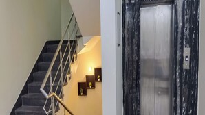 A staircase with a metal railing and a wall-mounted light fixture. - The Aroma Residency near The Medanta, The Medicity, Gurgaon (Gurugram)