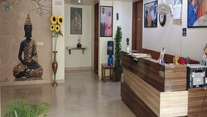 A reception area with a Buddha statue, a desk, and a wall with framed pictures. - The Aroma Residency near The Medanta, The Medicity, Gurgaon (Gurugram)
