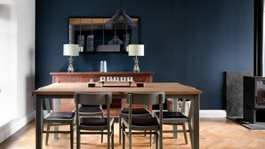 A dining area with a wooden table and chairs, a hanging light fixture, and a built-in cabinet above the table. - Meadow View Cottage (Carnforth)