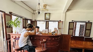 A bar area with wooden furniture, a potted plant, and a counter with various items including a Visa card. - Villa Thida Mekong Riverside (Luang Prabang)