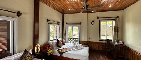 Une chambre d’hôtel avec deux lits, un plafond en bois, de grandes fenêtres et un plancher en bois.