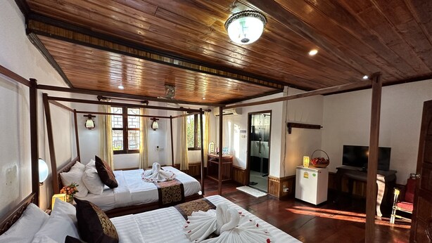 A room with two beds, wooden ceiling, and a television. - Villa Thida Mekong Riverside (Luang Prabang)