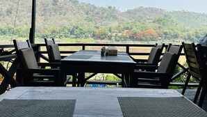 A restaurant with outdoor seating overlooking a river and hills. - Villa Thida Mekong Riverside (Luang Prabang)