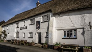 A traditional white building with a thatched roof, a sign reading "Duke of York," and outdoor seating. - Duke of York (Winkleigh)