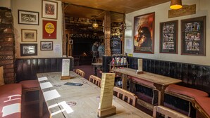 A pub with wooden furniture, a brick wall, and various framed pictures and posters on the walls. - Duke of York (Winkleigh)