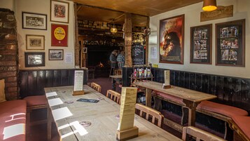 Um pub com móveis de madeira, parede de tijolos e diversas fotos e cartazes nas paredes.