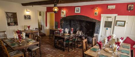 A traditional inn with wooden furniture, a stone fireplace, and red walls.