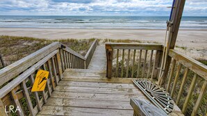 A wooden staircase leading to a beach with a dolphin crossing sign.