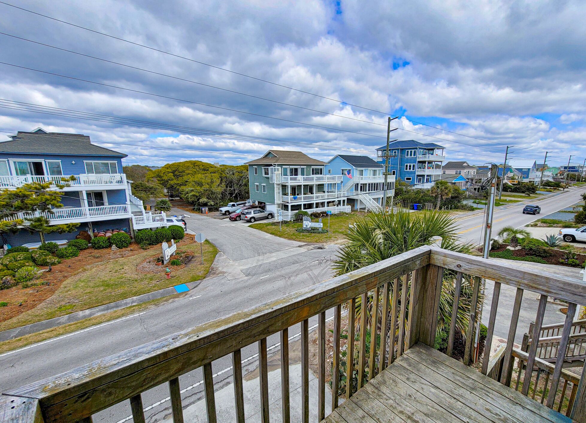 A coastal residential area with multi-story houses, a wooden deck, and a road.