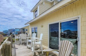 Une terrasse dotée de chaises Adirondack blanches et d’une porte vitrée donnant accès à un balcon.