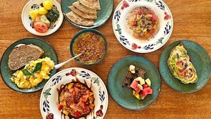 A variety of dishes on plates, including what appears to be a salad, a meat dish, and some bread. - The Garden (Paje)