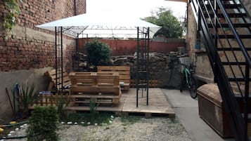 A patio area with a wooden bench, a white umbrella, and a metal staircase.