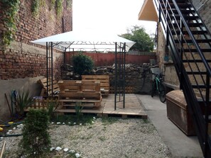 A patio area with a wooden bench, a white umbrella, and a metal staircase.