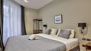 Ein Hotelzimmer mit einem großen Bett, einem Nachttisch, einer Wandlampe und einem Fenster mit Vorhängen.