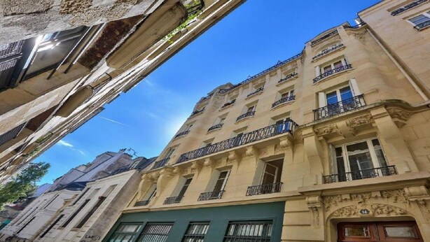 Ein mehrstöckiges Gebäude mit Balkonen und einer grünen Tür, typisch für Stadtarchitektur.