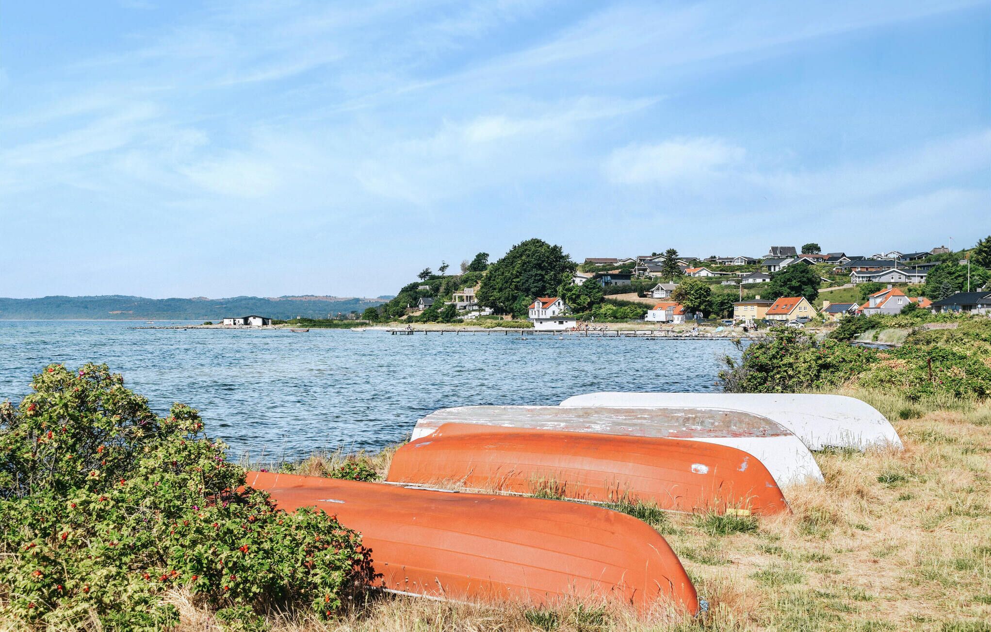 Eine Küstenlandschaft mit Häusern, Booten und blauem Himmel.
