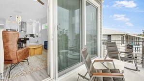 A modern interior with a dining area, a kitchen, and a balcony with seating.