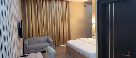 Una camera d'albergo con un letto, un divano, una scrivania e una televisione.