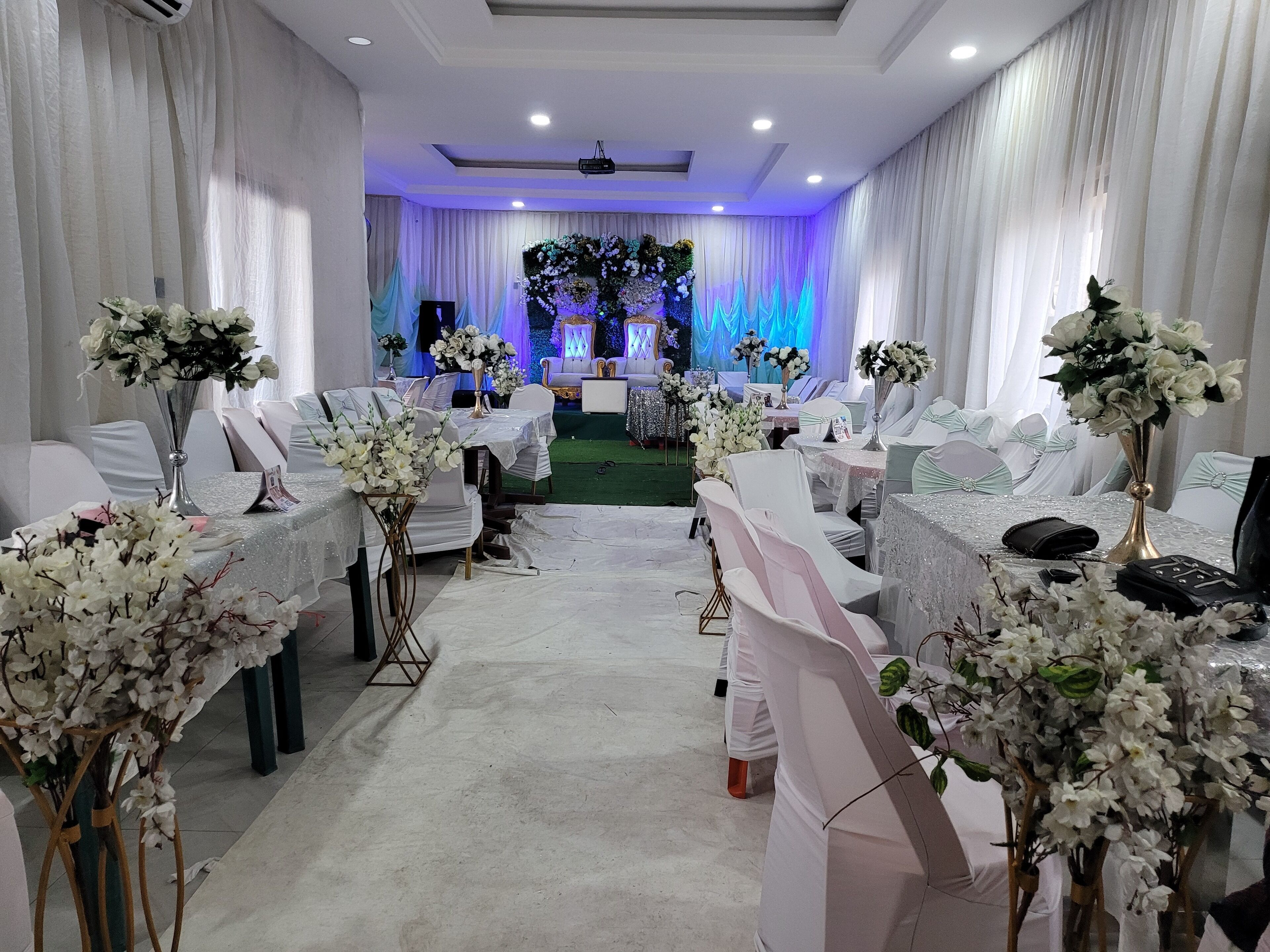 A wedding venue with white chairs, tables, and floral decorations.