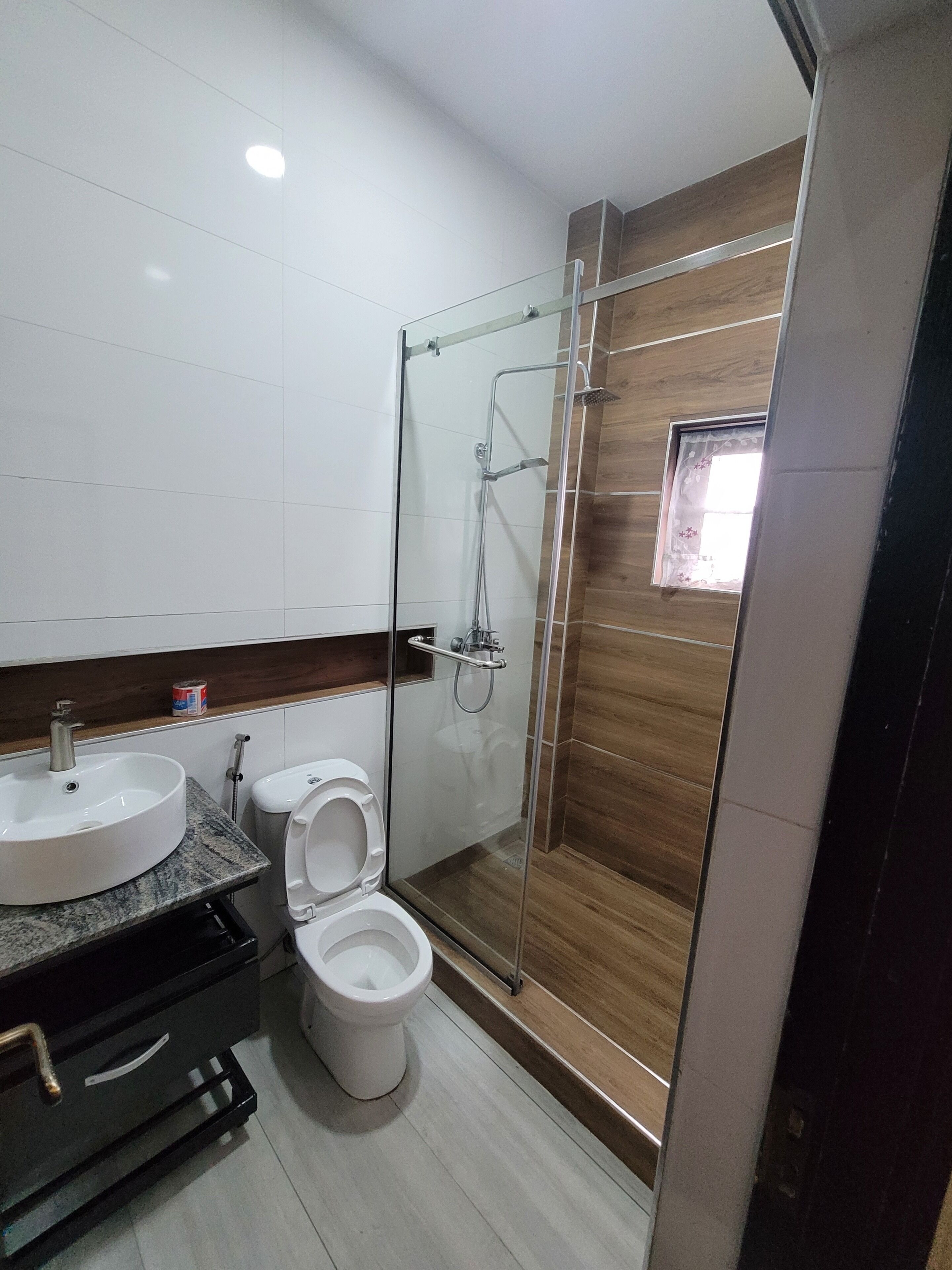 Une salle de bain moderne avec une douche à parois de verre, un lavabo blanc et des toilettes.