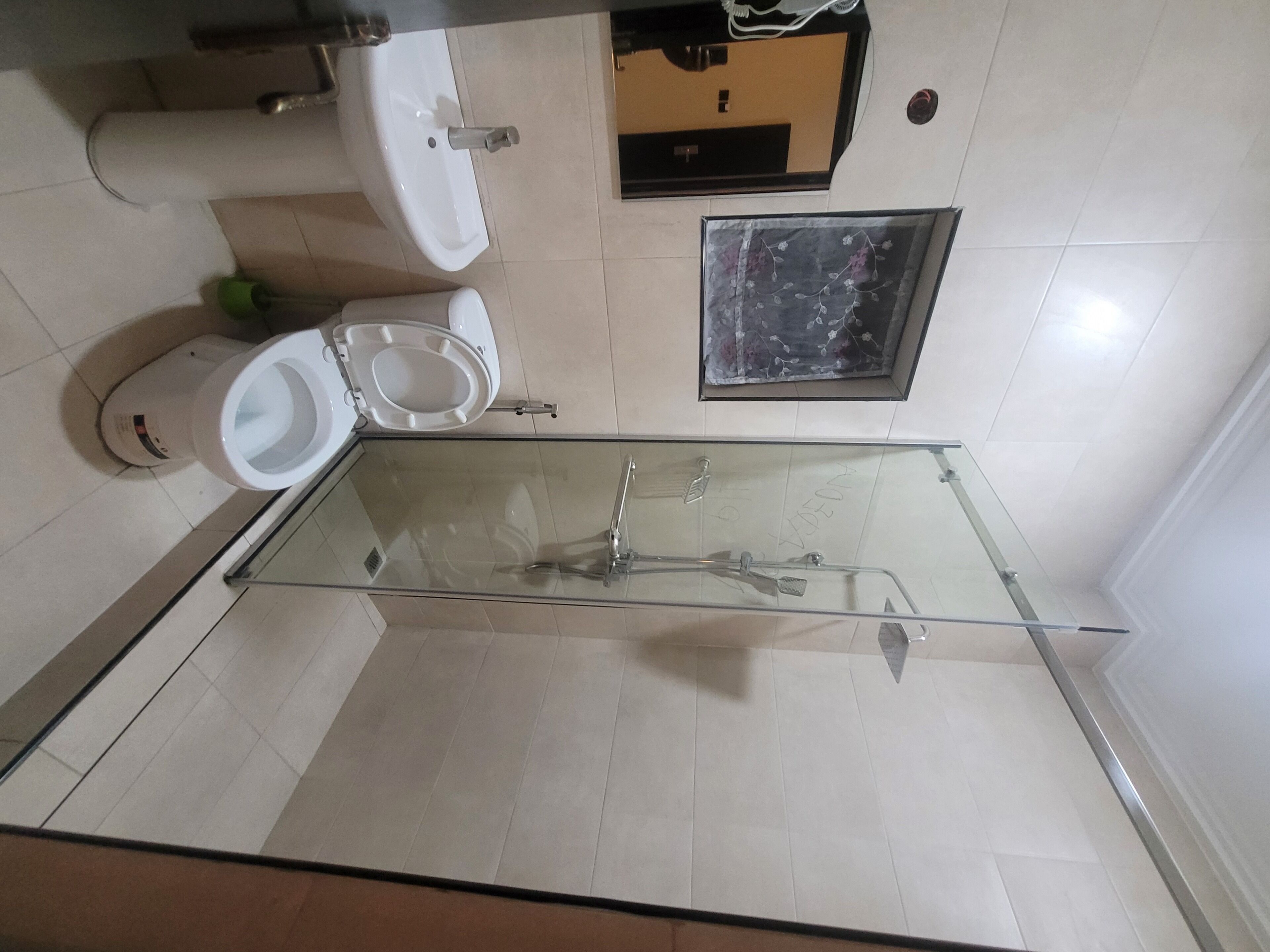 A bathroom with a glass-enclosed shower, a toilet, and a sink.