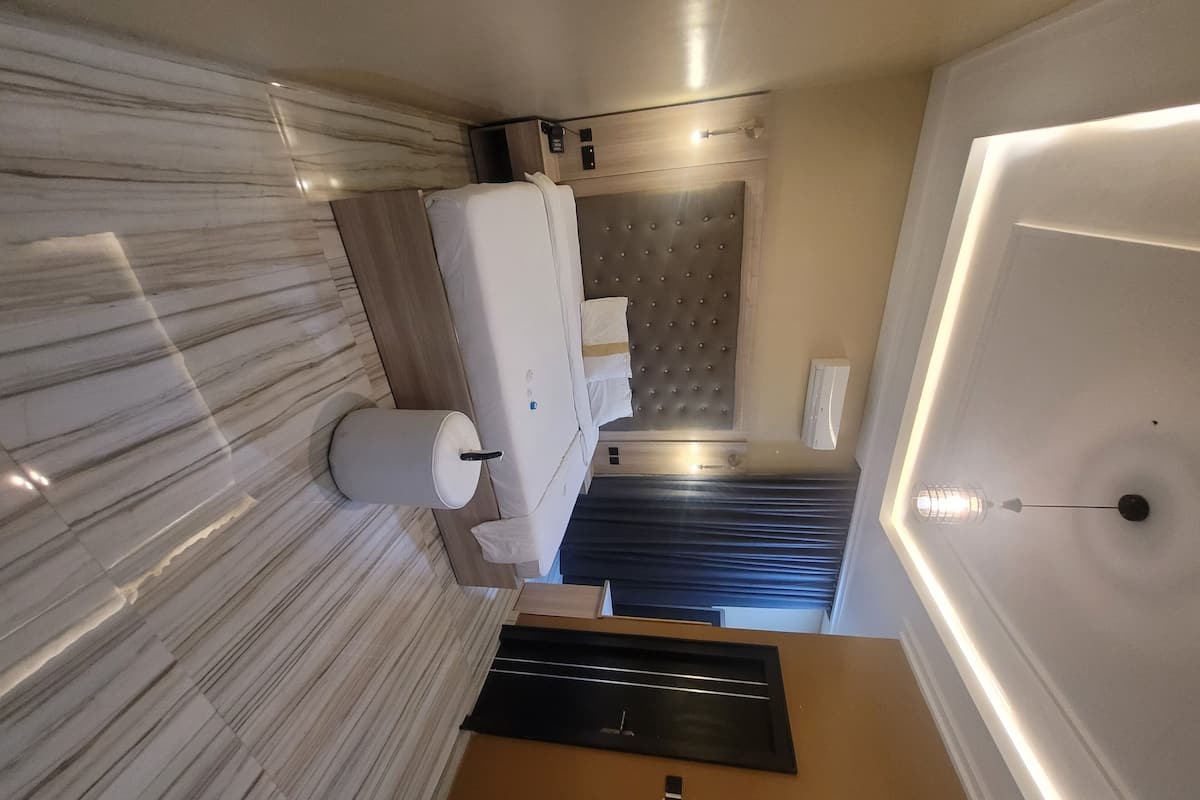 A modern bathroom with a marble floor, a large mirror, a toilet, and a shower area.
