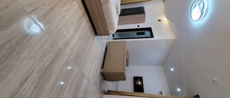 A modern interior with a wooden floor, a sofa, a coffee table, and a ceiling light fixture.