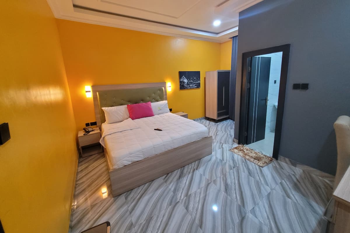 A hotel room with a bed, a wardrobe, a nightstand, and a door.
