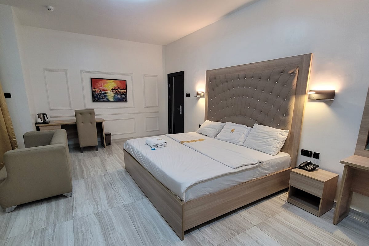 A modern hotel room with a large bed, a desk, and a chair.