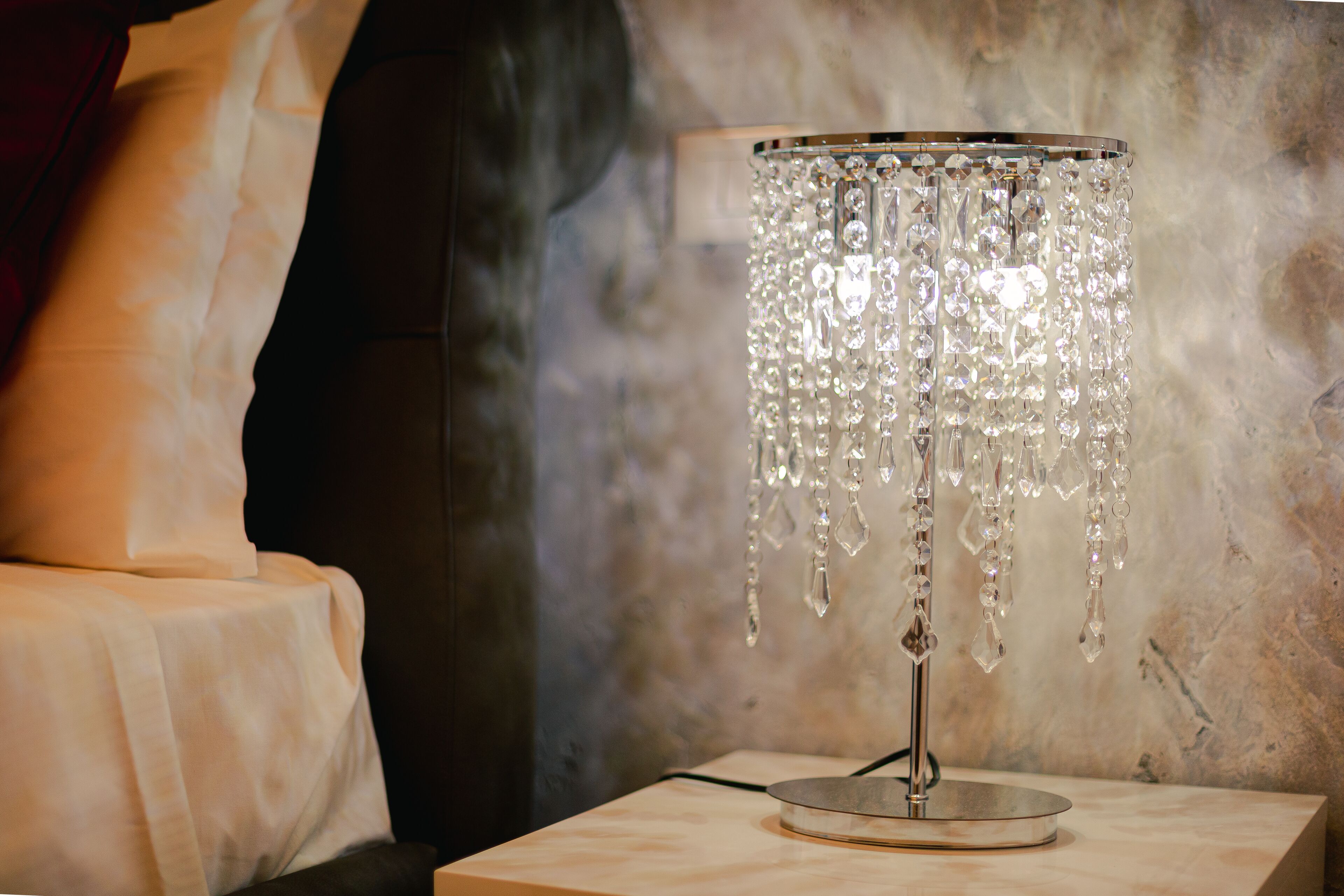 Una lámpara de mesa con base metálica y detalles de cristal, sobre una superficie de mármol.