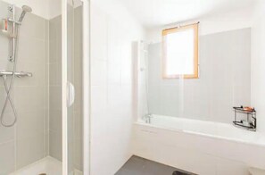 Bathroom features a glass-enclosed shower and a standalone bathtub with a handheld showerhead and standard faucet.