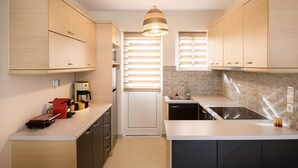 A compact kitchen with wooden cabinets, a built-in oven, and a sink. - Marathon Luxury Suites - Schinias Beach (Marathon)