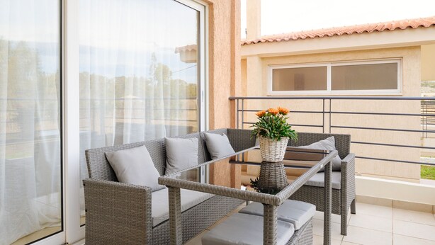 A balcony with wicker furniture, a glass table, and a potted plant. - Marathon Luxury Suites - Schinias Beach (Marathon)