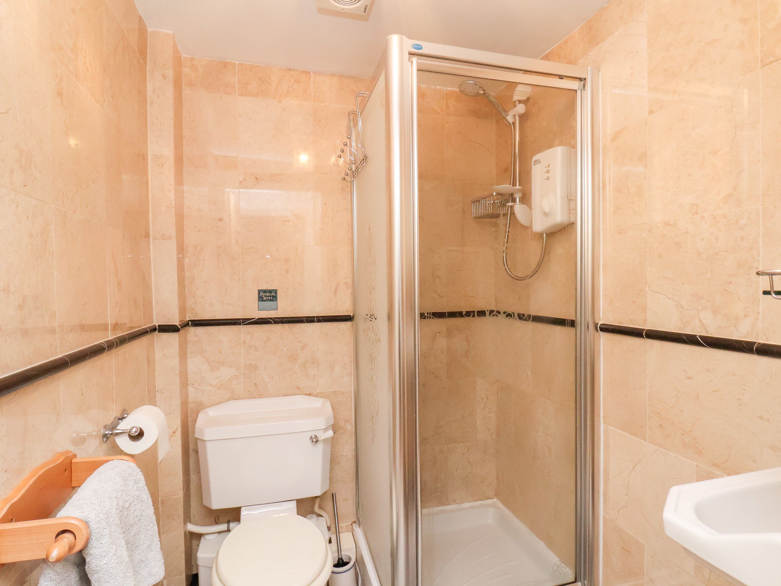A bathroom with a glass-enclosed shower, a toilet, and a sink.