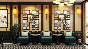 A room with three teal sofas, a patterned floor, and framed photographs on the wall. -  Omina Hanoi Hotel and Restaurant  (Hanoi)