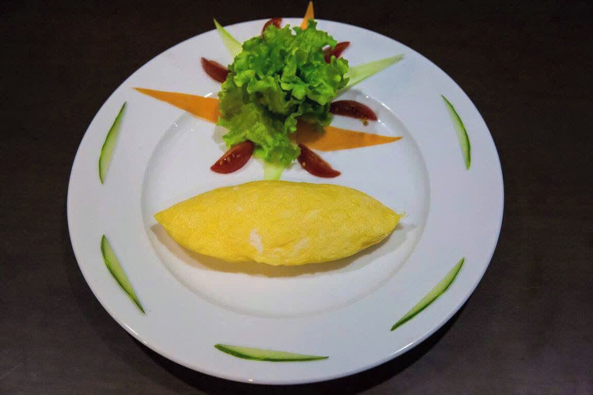 A plate with an omelette, lettuce, and cherry tomatoes.