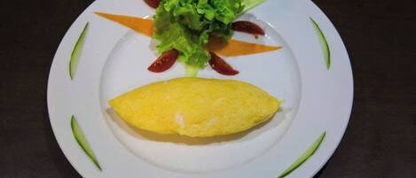 A plate with an omelette, lettuce, and cherry tomatoes.