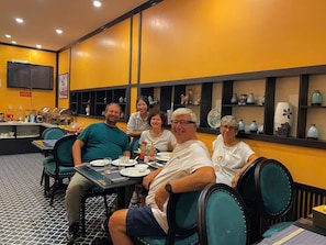 Diners enjoy meals in a vibrant dining area with tables, chairs, and a flat-screen TV.