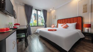 A hotel room with a large bed, a desk with a chair, a TV, and a window with curtains. -  Omina Hanoi Hotel and Restaurant  (Hanoi)