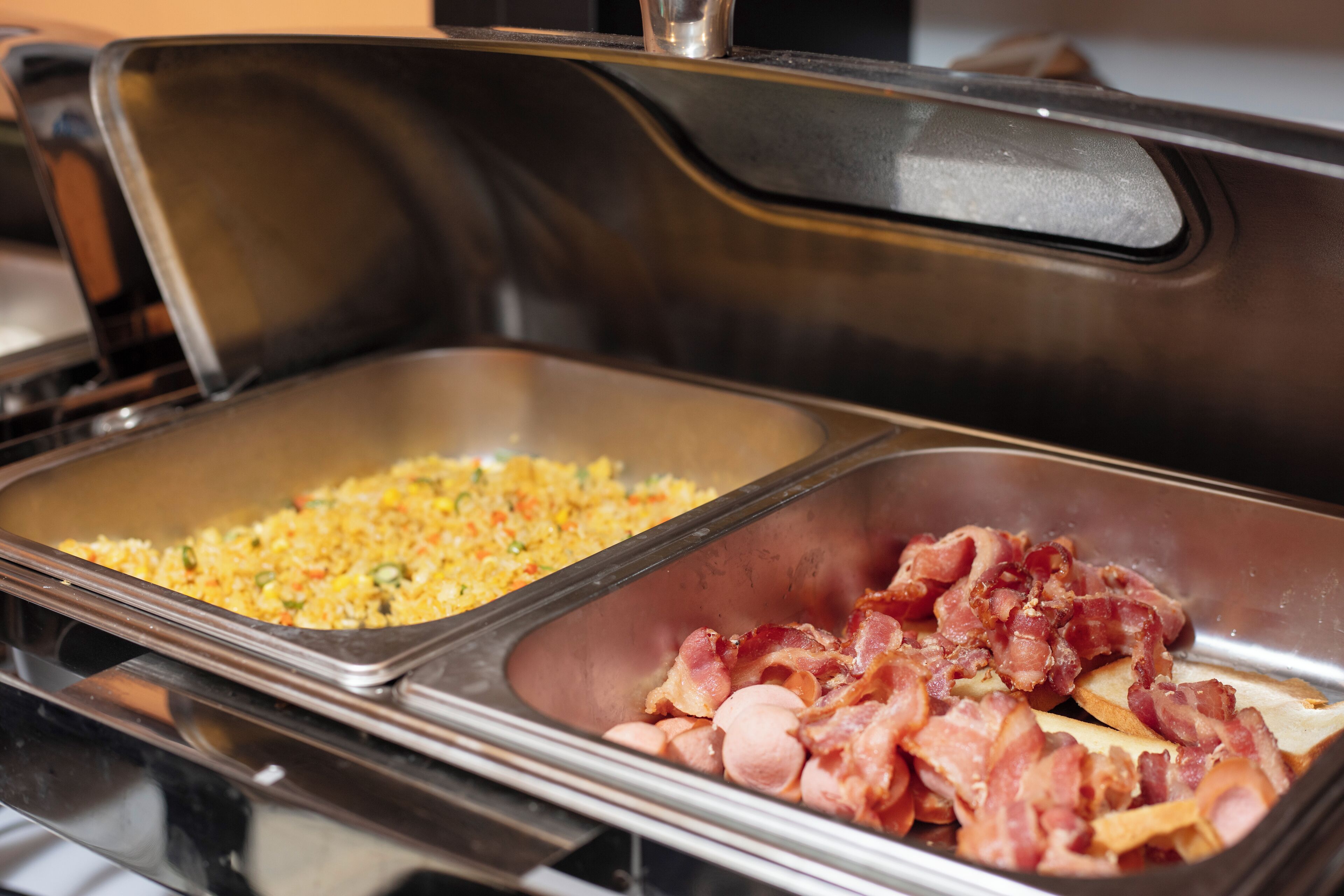 Ein Buffet mit zwei Speisen: gebratenem Reis und Speck.