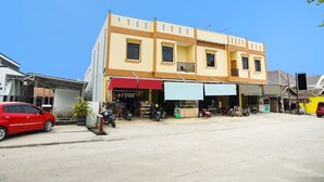 Un immeuble à plusieurs étages, avec un commerce au rez-de-chaussée et plusieurs motos garées devant.