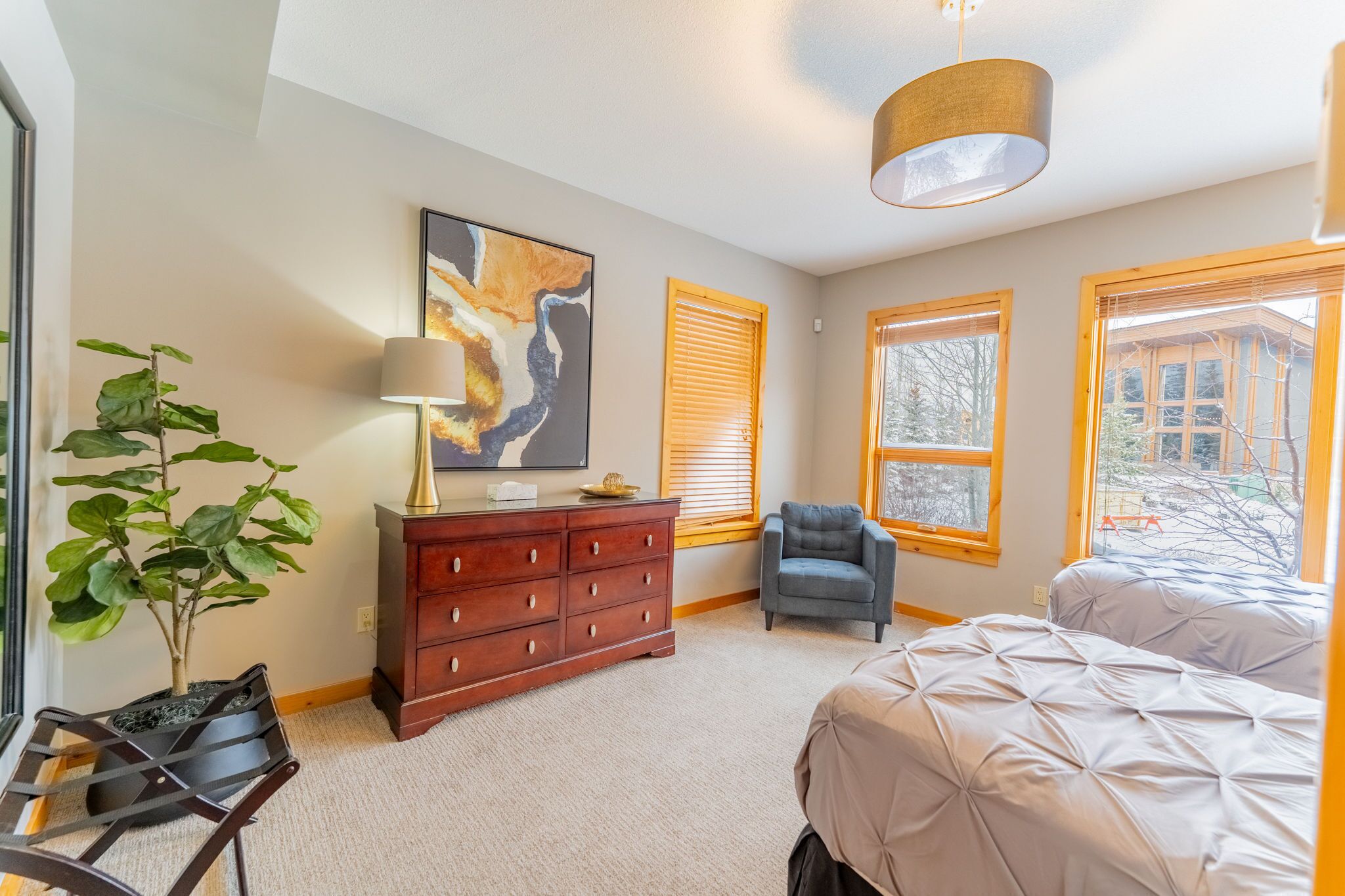 Een slaapkamer met een bed, een dressoir, een stoel en een schilderij aan de muur.