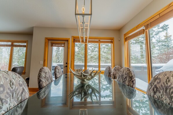 A dining area with a glass table, patterned chairs, and a central decorative piece.